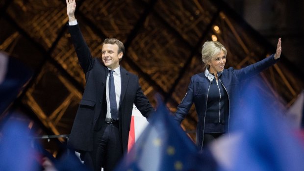 French President Emmanuel Macron and his wife Brigitte Trogneux wave in front of the Louvre Museum in Paris,