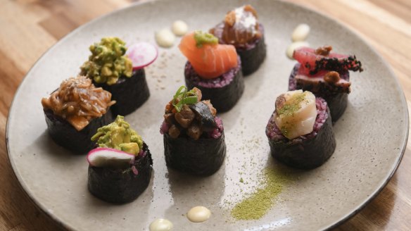 Purple rice nori rolls are sliced and garnished like nigiri-sushi hybrids.