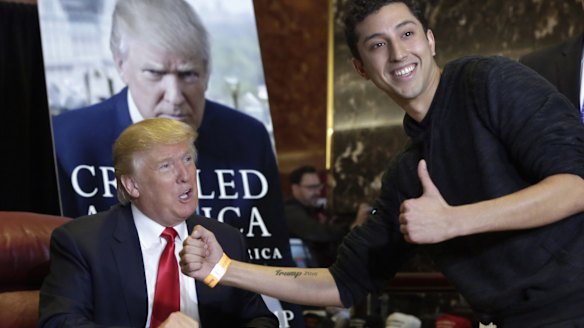 Jason Szkup of Leivittown, New York, shows his "Trump 2016" tattoo to Republican presidential candidate Donald Trump as Trump autographs copies of his new book at Trump Tower, in New York.