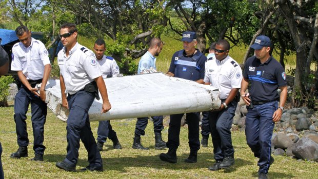 French police officers carry the flaperon which washed up on Reunion Island.