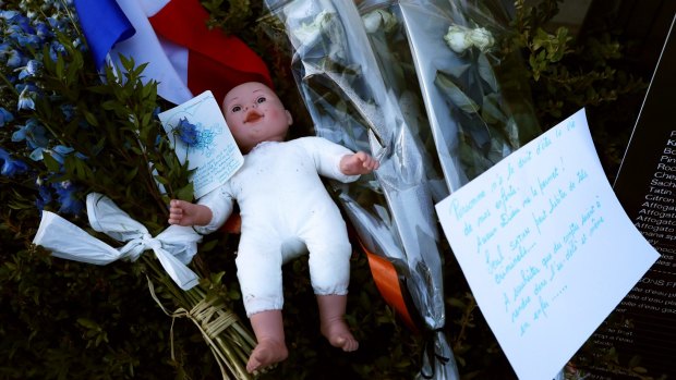 A childs doll sits next to a French flag and tributes to the victims of a terror attack on the Promenade des Anglais 
