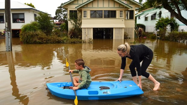 Binti Jones (right) and her son Matthew Jones 5 paddle along a flooded Bright street towards their home in Lismore.