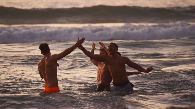 A group of men celebrate the new year as the sun rises over Bondi Beach.
