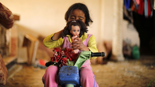 A Palestinian girl plays with a doll inside a destroyed building in Beit Hanun in the northern Gaza Strip. 