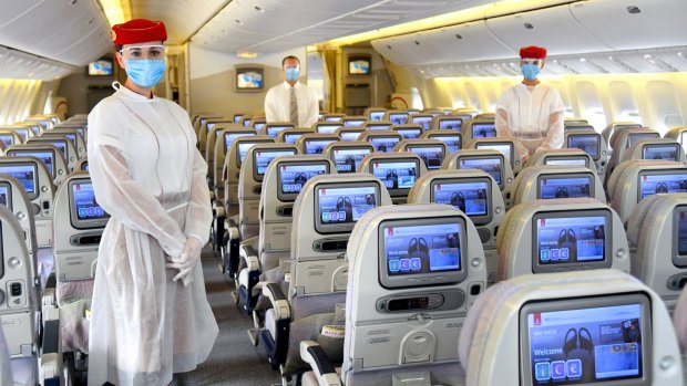 Emirates cabin crew wear personal protective equipment on flights to guard against COVID-19. Australians are in limbo regarding when we might be able to travel normally again.