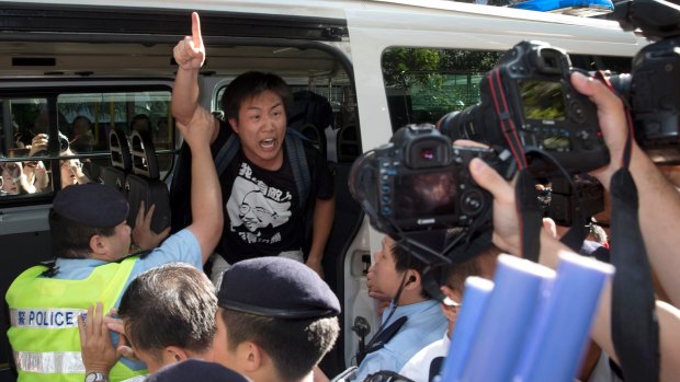 A pro-democracy activist is taken way by police after the group's march clashed with pro-China counter protesters.