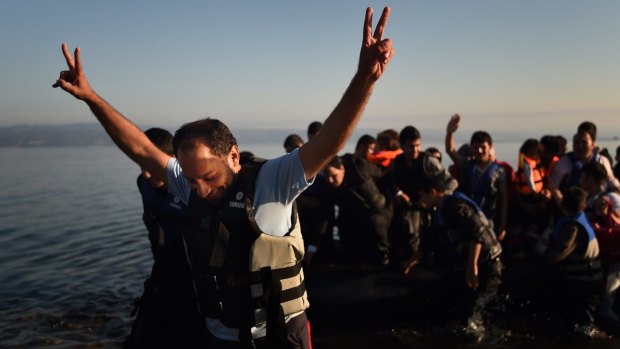 A Syrian man gives the V for victory sign as the boat he was on with approximately 45 refugees from Syria, Iraq and Afghanistan onboard arrives at the Greek island of Lesvos after a three hour journey from Turkey. 