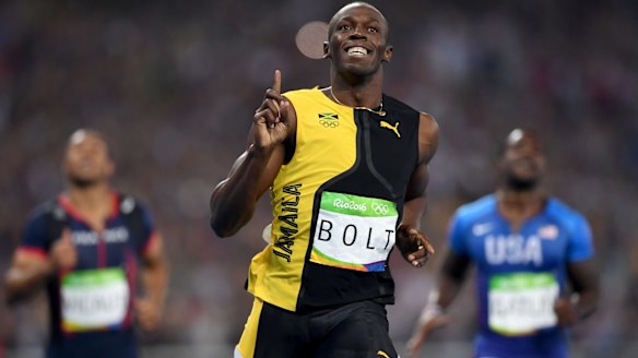 Three-time champion: Usain Bolt celebrates winning the 100m final, with Justin Gatlin, right, finishing second.