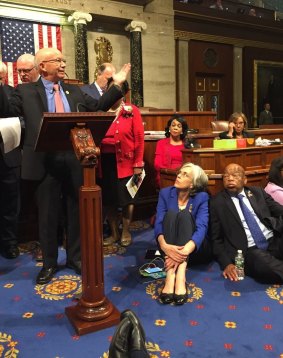 Democrat members of Congress speaking, sitting down on floor during sit-down protest.