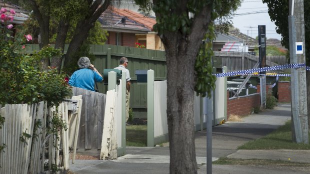 Neighbours look across their yards to the crime scene.