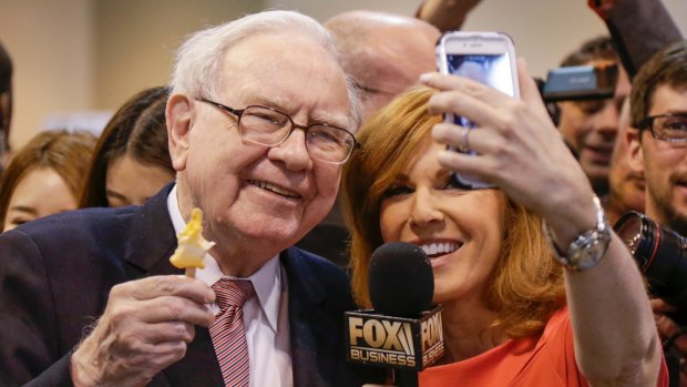 Berkshire Hathaway Chairman and CEO Warren Buffett, holds an ice cream as he poses for a selfie with Liz Claman of the Fox Business Network during the annual Berkshire Hathaway shareholders meeting in Omaha, Nebraska.