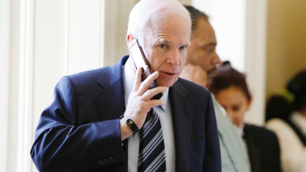 Senator John McCain talks on the phone outside a Republican Caucus.