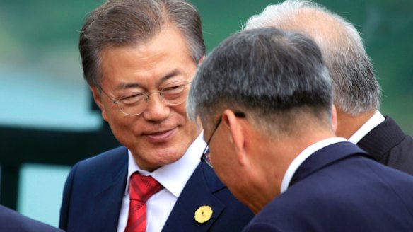 South Korean President Moon Jae-in talks with other leaders before an APEC photo call on Saturday.