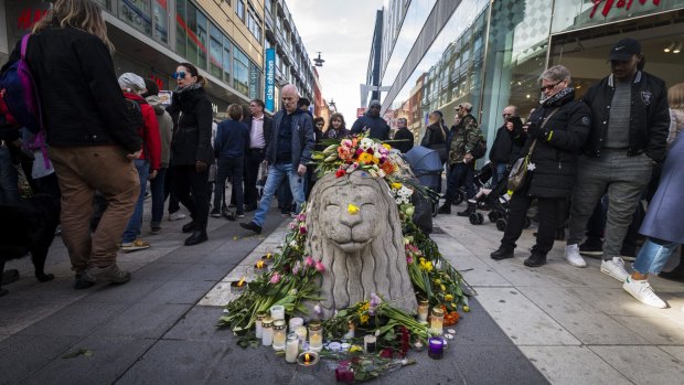 Flowers and candles adorn a Drottninggatans lion statue on Sunday in Stockholm.