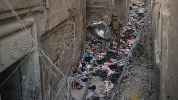 An Iraqi Special Forces soldier walks through clothes left behind by fleeing civilians.