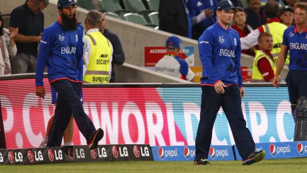 A dejected England opener Moeen Ali and captain Eoin Morgan walk onto the field after the game ended.