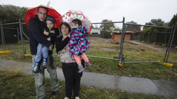 Chris and Christina Pilkington, with their children Theodore, 4, and Isabelle, 2, in front of the Mr Fluffy demolition site they have bought back and plan to rebuild.