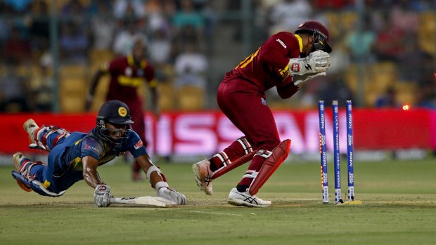 Denesh Ramdin breaks the stumps to run out Sri Lanka's Dinesh Chandimal in Bangalore.
