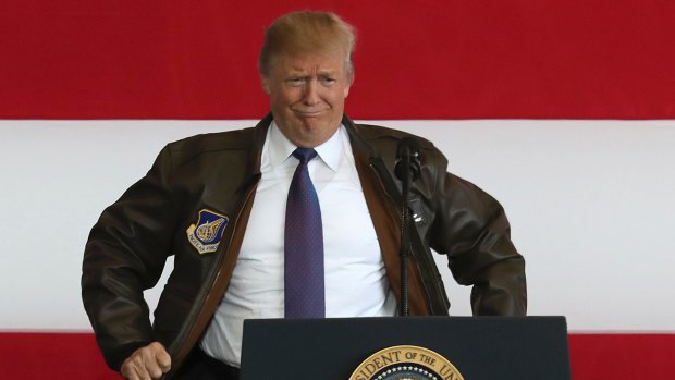 President Donald Trump puts on a military jacket as he meets the US troops at the U.S. Yokota Air Base, on the outskirts of Tokyo on Sunday