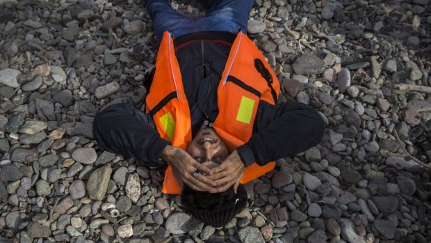 A man lies on a beach after arriving in a dinghy from the Turkish coast to the Greek island of Lesbos on Tuesday.