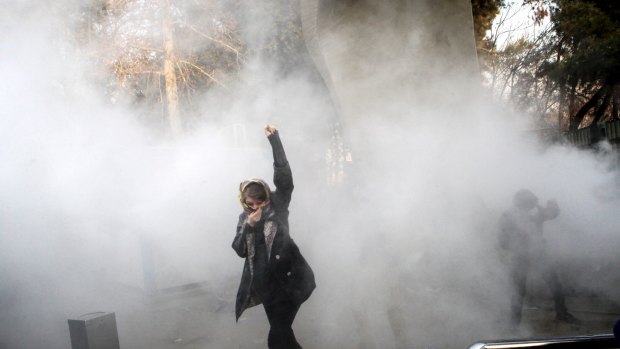 In this photo obtained but not taken by the Associated Press, a university student attends a protest last week inside Tehran University while a smoke grenade is thrown by anti-riot Iranian police.