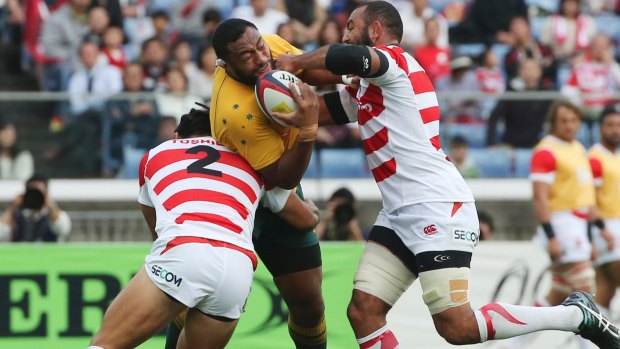 Australia's Sekope Kepu is tackled by Shota Horie, left, and Leitch Michael, right.