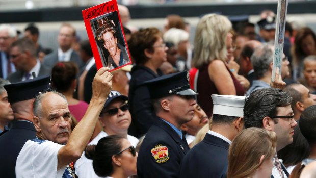 A man at New York's September 11 memorial ceremony holds aloft a photo of a loved one lost in the attacks.