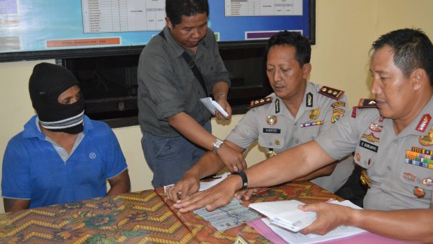 Captain Yohanis Humiang (left) looks on as head of the people smuggling division of Nusa Tenggara Timur, Ibrahim, Rote police chief Hidayat and East Nusa Tenggara Timur police chief General Endang Sunjaya count money in June.