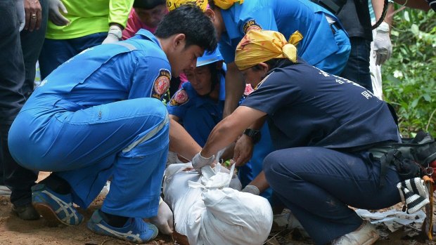 Rescue workers lift a bag containing human remains found in shallow graves in southern Thailand.