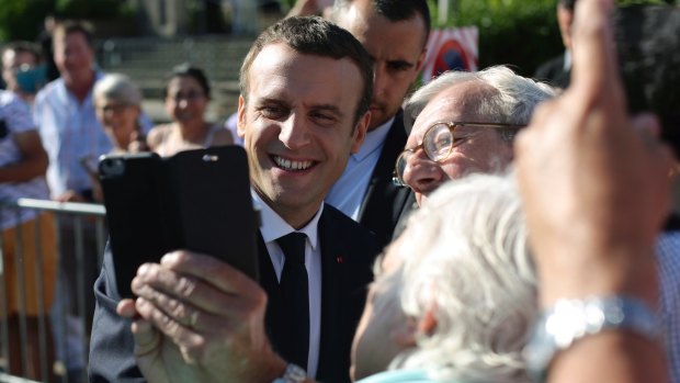 Emmanuel Macron poses for a selfie after voting in the final round of parliamentary elections. The new French president is riding a wave of popularity.