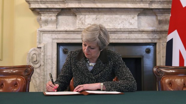 Britain's Prime Minister Theresa May signs the official letter to European Council President Donald Tusk.