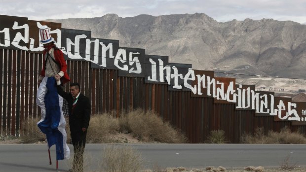 Protestors dressed as a diabolical Uncle Sam, on stilts, and Mexico's President Enrique Pena Nieto hold hands as they walk along the border fence in Ciudad Juarez.