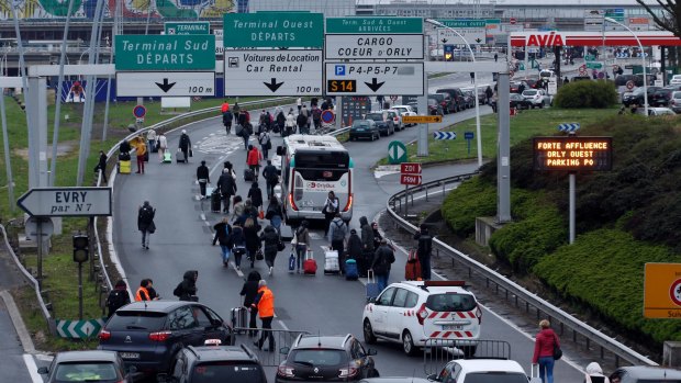 Travellers walk on the highway to the Orly airport, south of Paris, which was evacuated after a man was fatally shot there.