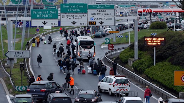 Travellers walk on the highway to the Orly airport, south of Paris, which was evacuated after a man was fatally shot there.