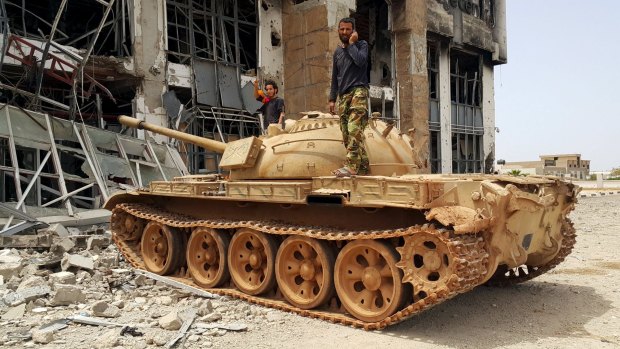 Members of the Libyan pro-government forces stand on a tank in Benghazi, Libya in May.