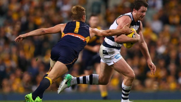 Patrick Dangerfield attempts to break from a tackle by Sam Mitchell of the Eagles.