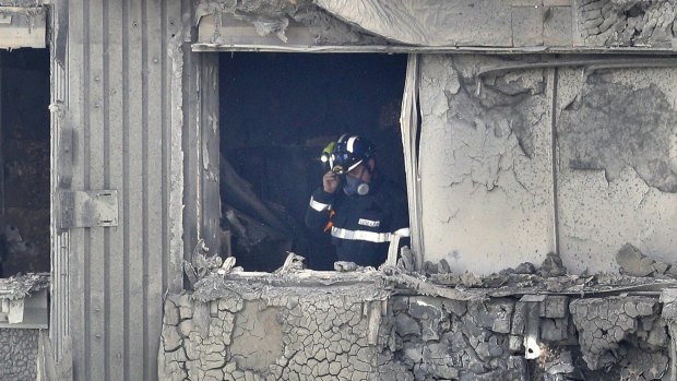 A firefighter conducts a search of a burnt-out flat in Grenfell Tower.