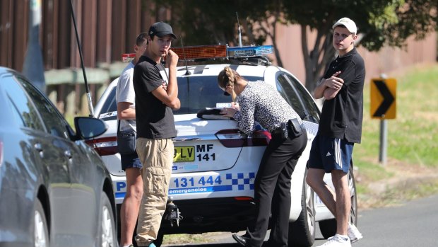 Police detectives talk to teenagers close to a house after a 15-year-old boy was shot in the head at a home in Glenfield. 