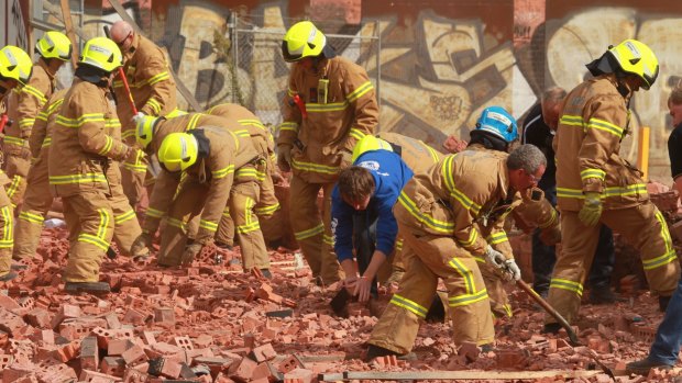 Firemen and workers frantically dig in the rubble of the fallen wall in March 2013. Three people died when the structure fell on them.