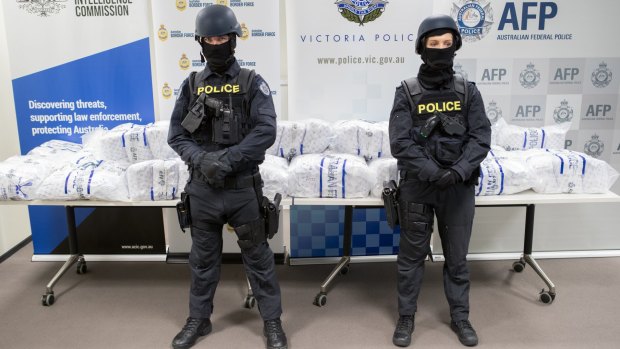 Police stand in front of the seized drugs.