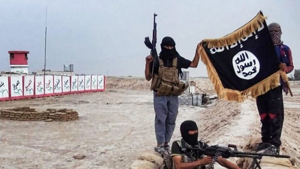 IS fighters pose with a Jihadist flag in the northern Iraqi province of Salahuddin.