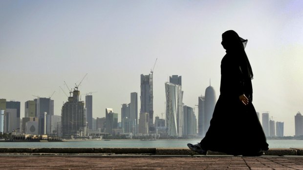 A woman walks in front of the city skyline in Doha, Qatar's capital.
