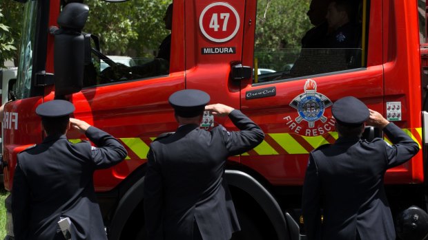 Firefighters salute as a firetruck from Mildura emblazoned with the number 47, drives past.