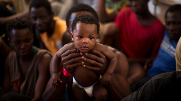 A man from Nigeria holds his 6 months old baby, on their way to Italy after being rescued along with more than 600 migrants from the Mediterranean Sea on June 16.