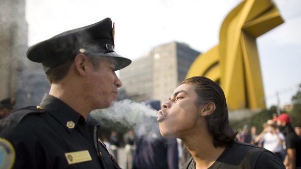 A protester blows marijuana smoke in the face of a police officer in Mexico City.