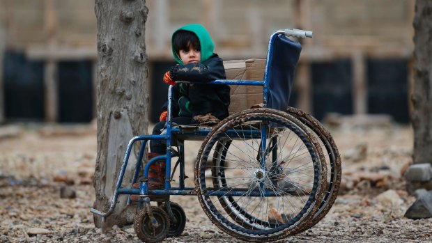 A Syrian child sits on a wheelchair after he and his family crossed into Turkey on Friday.  
