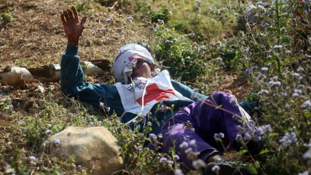 An injured Myanmar Red Cross volunteer lies on the ground after vehicles of a rescue convoy were attacked by Kokang rebels near Laukkai, northern Shan State, in Myanmar.