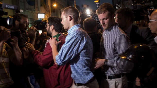 US Olympic swimmers Gunnar Bentz, left, and Jack Conger are mobbed by the media and booed by onlookers while leaving the police station.