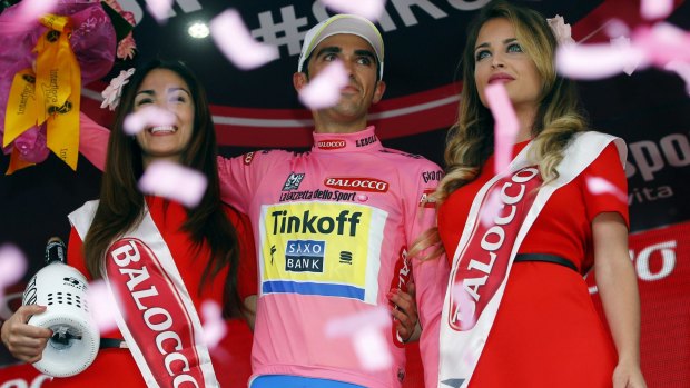Spain's Alberto Contador stands next to hostesses on the podium as he celebrates retaining the overall leader's pink jersey.