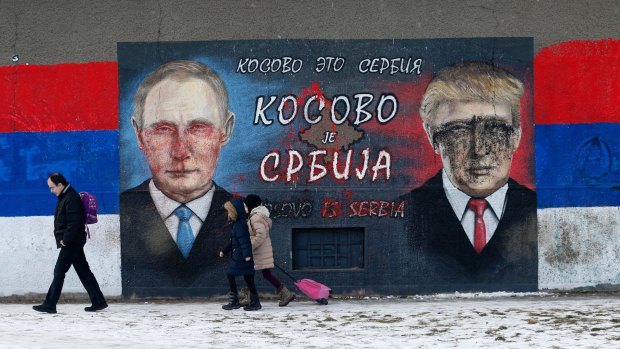 People walk by Serb nationalist graffiti depicting Russian President Vladimir Putin, left, and US President Donald Trump in Belgrade.